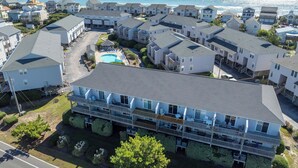 A coastal residential area with multiple two-story houses, a central swimming pool, and a view of the ocean. - Enjoy a relaxing stay at Lazy Days, Public Pool, Beach Access, short walk to Park (Surf City)
