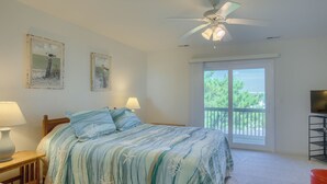 A bedroom with a bed, two bedside lamps, a ceiling fan, a TV stand, and a balcony with a view. - Enjoy a relaxing stay at Lazy Days, Public Pool, Beach Access, short walk to Park (Surf City)
