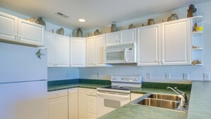A kitchen with white cabinets, a microwave, stove, and a sink. - Enjoy a relaxing stay at Lazy Days, Public Pool, Beach Access, short walk to Park (Surf City)
