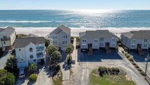 A beachfront residential area with multiple two-story houses, a parking area, and a clear view of the ocean. - Enjoy a relaxing stay at Lazy Days, Public Pool, Beach Access, short walk to Park (Surf City)