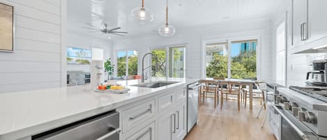 A modern kitchen with a large island, stainless steel appliances, and a view of the outdoors.