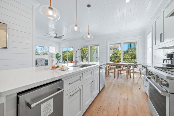 A modern kitchen with a large island, stainless steel appliances, and a view of the outdoors.