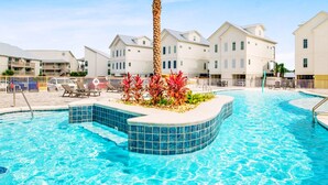 A swimming pool with a palm tree and red plants, surrounded by white buildings with balconies. - Luxury 5BR, Pool, Walk To Beach, Private Boat Slip & Fishing Pier, Sleeps 15 (Orange Beach)