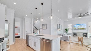 A modern kitchen with white cabinetry, a stainless steel dishwasher, pendant lighting, and a large island. - Luxury 5BR, Pool, Walk To Beach, Private Boat Slip & Fishing Pier, Sleeps 15 (Orange Beach)