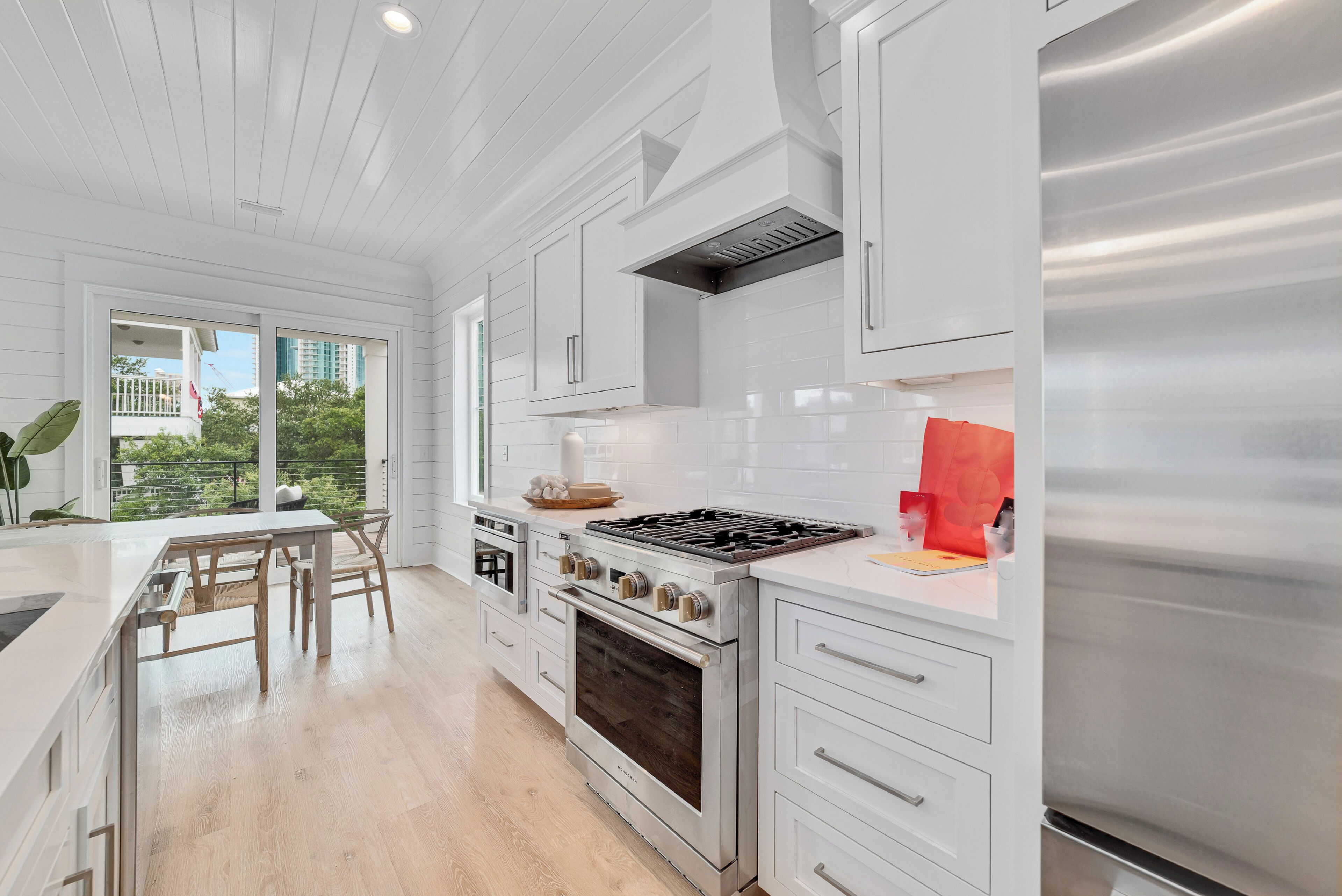 A modern kitchen with white cabinetry, a stainless steel stove, and an oven.