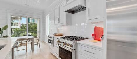 A modern kitchen with white cabinetry, a stainless steel stove, and an oven.