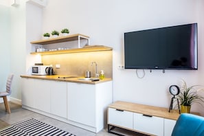 A modern kitchen with a built-in microwave, kettle, and sink. A flat-screen TV is mounted on the wall above the counter. - Cracow Rentals Zacisze (Kraków)