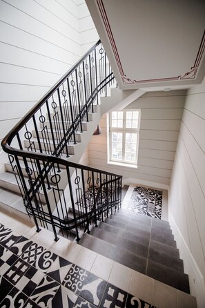 Un escalier avec des rampes en métal noir et des carreaux de sol à motifs.