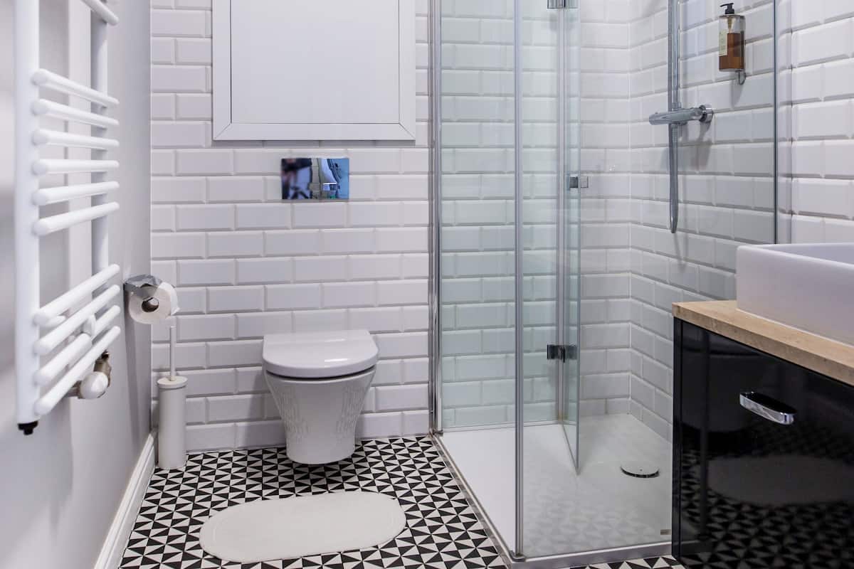 Un bagno moderno con doccia vetro, un water bianco e un lavabo con piano in legno.