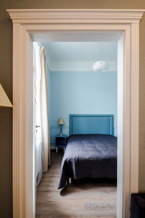 A bedroom with a bed, a nightstand, a lamp, and a hanging light fixture. - Cracow Rentals Zacisze (Kraków)