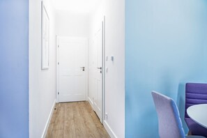 A narrow hallway with wooden flooring, white walls, and a closed door at the end. - Cracow Rentals Zacisze (Kraków)