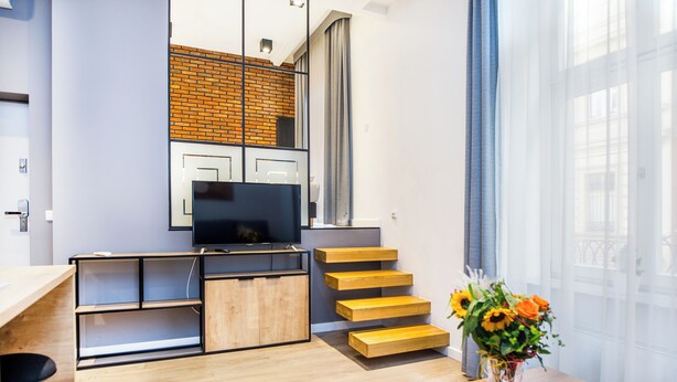 Uma sala de estar moderna com televisão de tela plana, móveis de madeira e uma escada.