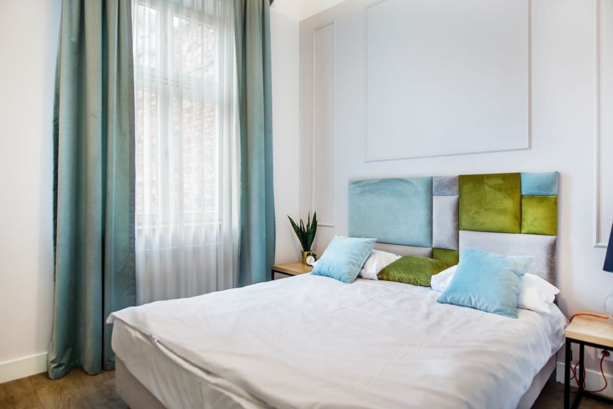 Une chambre avec un grand lit, une table de chevet ornée d’une plante et une œuvre d’art accrochée au mur.