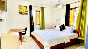 Un dormitorio con cama, escritorio, silla y ventana con cortinas.