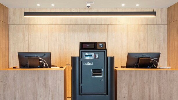 A modern hotel room with a wooden wall paneling, a central black minibar, and two laptops on wooden desks. - B&B Hotel Vila Do Conde (Vila do Conde)