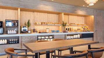 A modern kitchen with a wooden countertop, a microwave, and a coffee station.