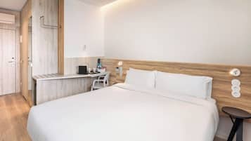 A modern hotel room with a large bed, a desk, and a chair.