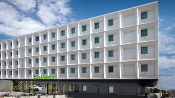 A modern B&B hotel with a grid-like facade, multiple balconies, and a gravel courtyard.