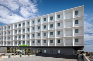 A modern B&B hotel with a grid-like facade, multiple balconies, and a gravel courtyard.