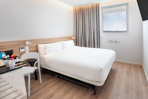 A hotel room with a bed, a desk with a chair, a window, and curtains. - B&B Hotel Vila Do Conde (Vila do Conde)