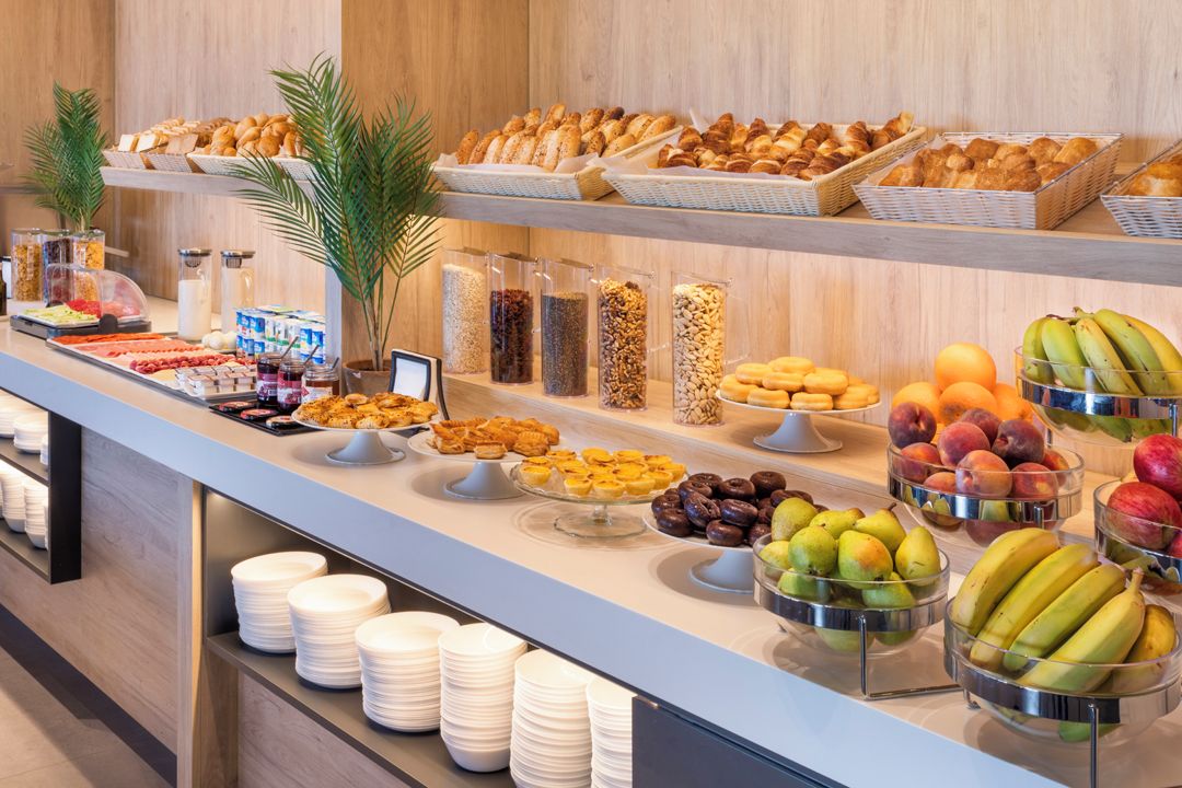 Buffet com diversos alimentos, incluindo frutas, doces e cereais.