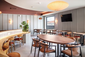 Un comedor moderno con mesas y sillas de madera, una barra y un amplio ventanal con vistas.