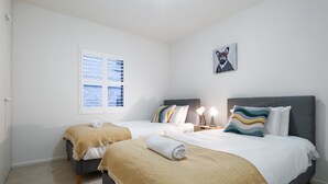 A hotel room with two beds, a window with blinds, a framed picture on the wall, and a bedside table with a lamp. - Riverside 2-bed Apartment With Balcony & Parking (Melbourne)