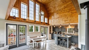 A spacious kitchen with a large island, wooden ceiling, and large windows. - S Diamond S Retreat | Huge Backyard & Hot Tub – 2 Miles to Town! (Rangeley)