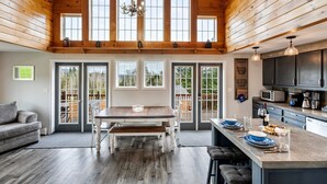 A spacious kitchen with a large island, wooden ceiling, and large windows. - S Diamond S Retreat | Huge Backyard & Hot Tub – 2 Miles to Town! (Rangeley)