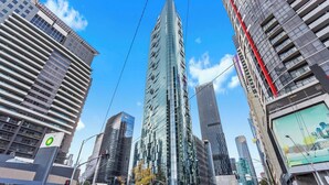 A modern urban street with tall buildings, including a prominent glass skyscraper. - Stylish Southbank 1-bed Flat With Luxury Amenities (Melbourne)