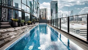 A rooftop pool with a city view, surrounded by modern buildings and potted plants. - Stylish Southbank 1-bed Flat With Luxury Amenities (Melbourne)