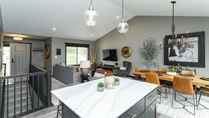 A modern kitchen with a marble countertop, pendant lights, and a dining area with a wooden table and chairs. - Spacious 4-bedroom house in peaceful neighborhood 10min from Mayo Clinic. (Rochester)