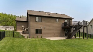 A two-story building with a flat roof, a balcony on the second floor, and a staircase leading to the upper level. - Spacious 4-bedroom house in peaceful neighborhood 10min from Mayo Clinic. (Rochester)