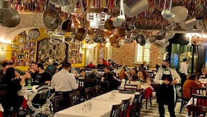 Un restaurante animado con varias mesas, comensales y un camarero.