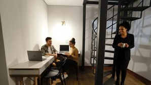 Un espacio de oficina moderno con un escritorio blanco, dos portátiles y una escalera de caracol.