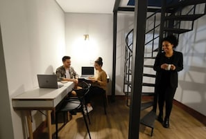 Un espacio de oficina moderno con un escritorio blanco, dos portátiles y una escalera de caracol.