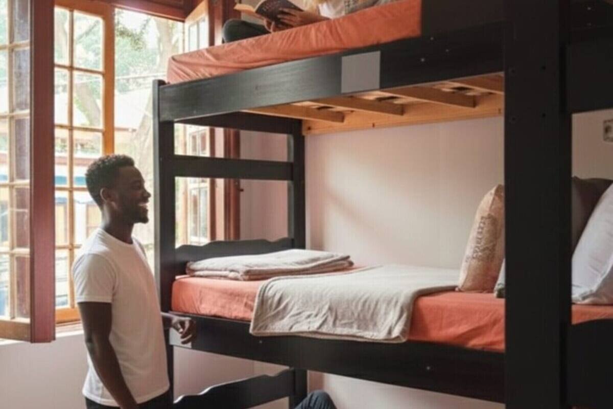 Una camera con un letto a castello, una persona in piedi e un'altra sdraiata sul letto inferiore.