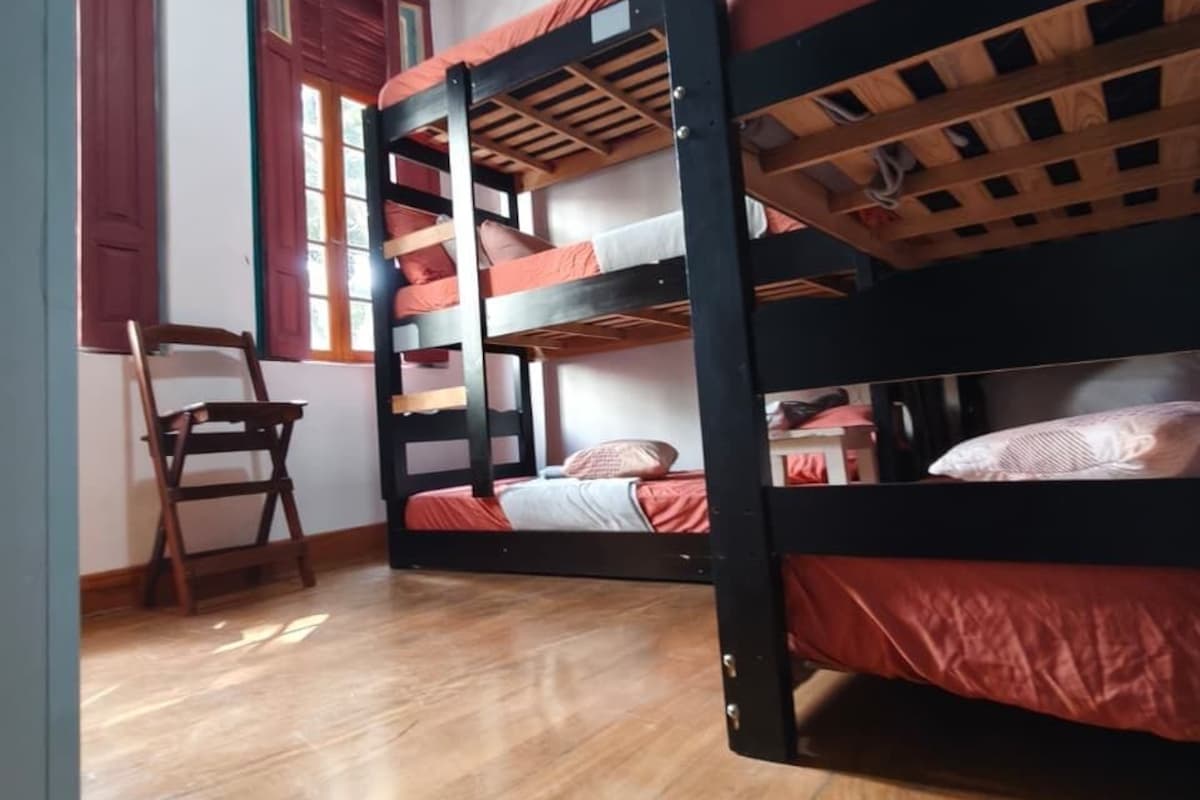 Una habitación con literas, suelo de madera y una silla.