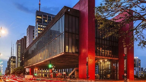 Un edificio moderno con una estructura roja llamativa, ventanas amplias y una entrada visible.
