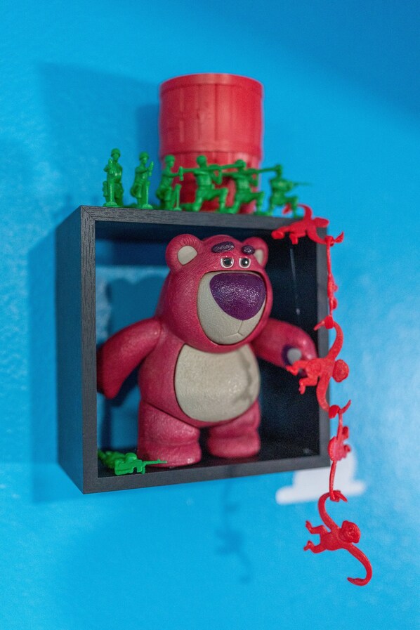 A red bear figurine in a display case with a blue background. - Imaginationville (Ozark)