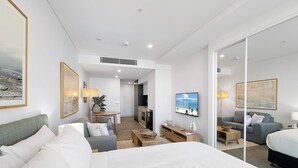 Une chambre d’hôtel moderne dotée d’un grand lit, d’un canapé, d’une télévision et d’un coin repas.