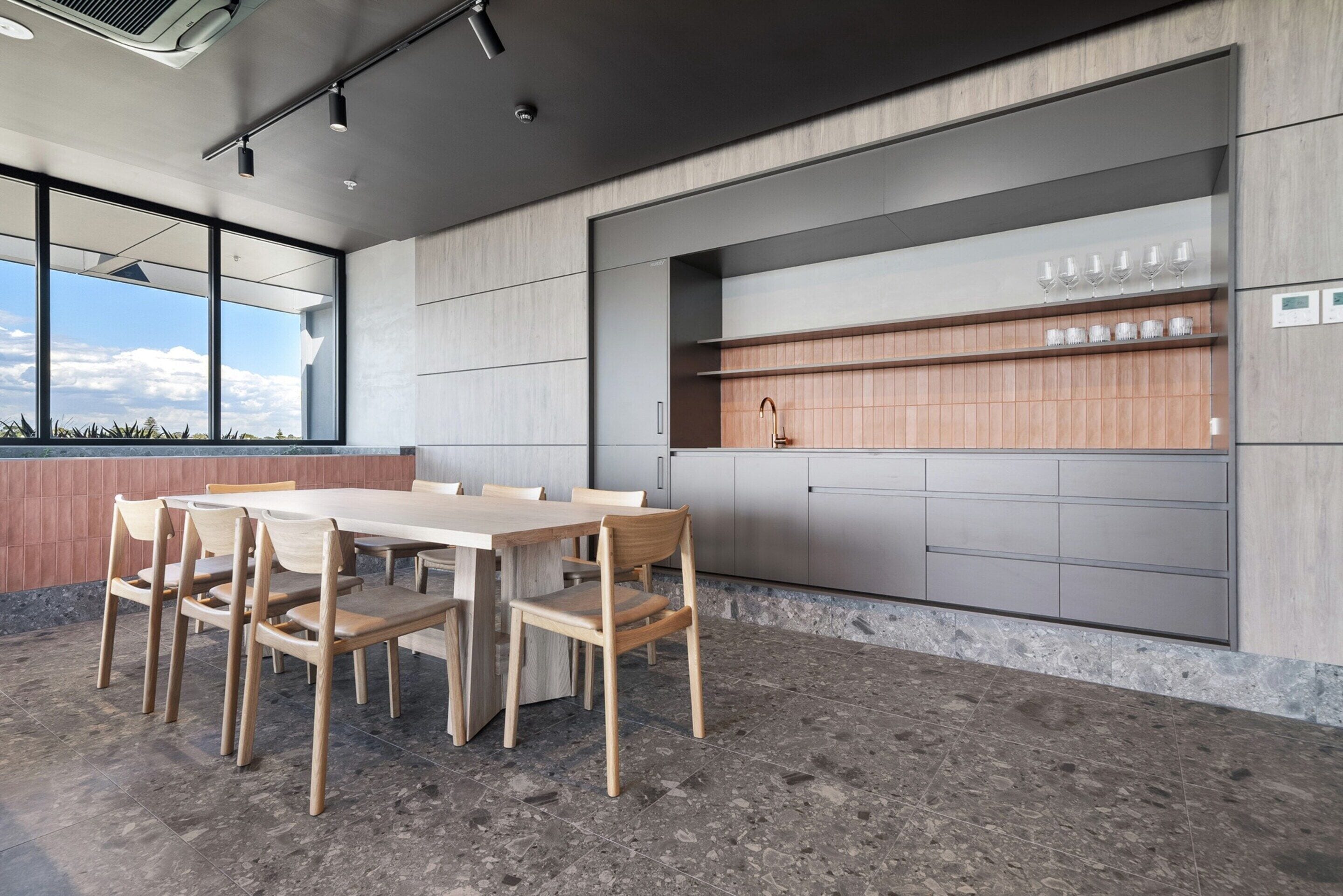 A modern kitchen with a large island, built-in cabinets, and a dining area with a wooden table and chairs.