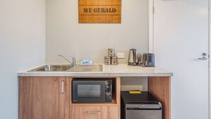 A compact kitchenette with a sink, toaster, kettle, and microwave. - Woolshed Suites (Lake Tekapo)