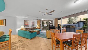 A spacious living area with a sofa, dining table, and chairs, a ceiling fan, and a view of the outdoors. - Stylish 3BR Oceanfront Stay by Mooloolaba Esp (Sunshine Coast)