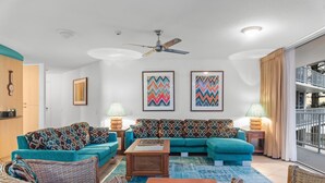 A living room with teal sofas, a wooden coffee table, wicker chairs, and a ceiling fan. - Stylish 3BR Oceanfront Stay by Mooloolaba Esp (Sunshine Coast)