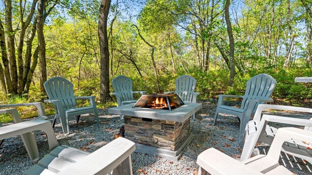 Un foyer entouré de fauteuils Adirondack, situé dans une zone boisée.