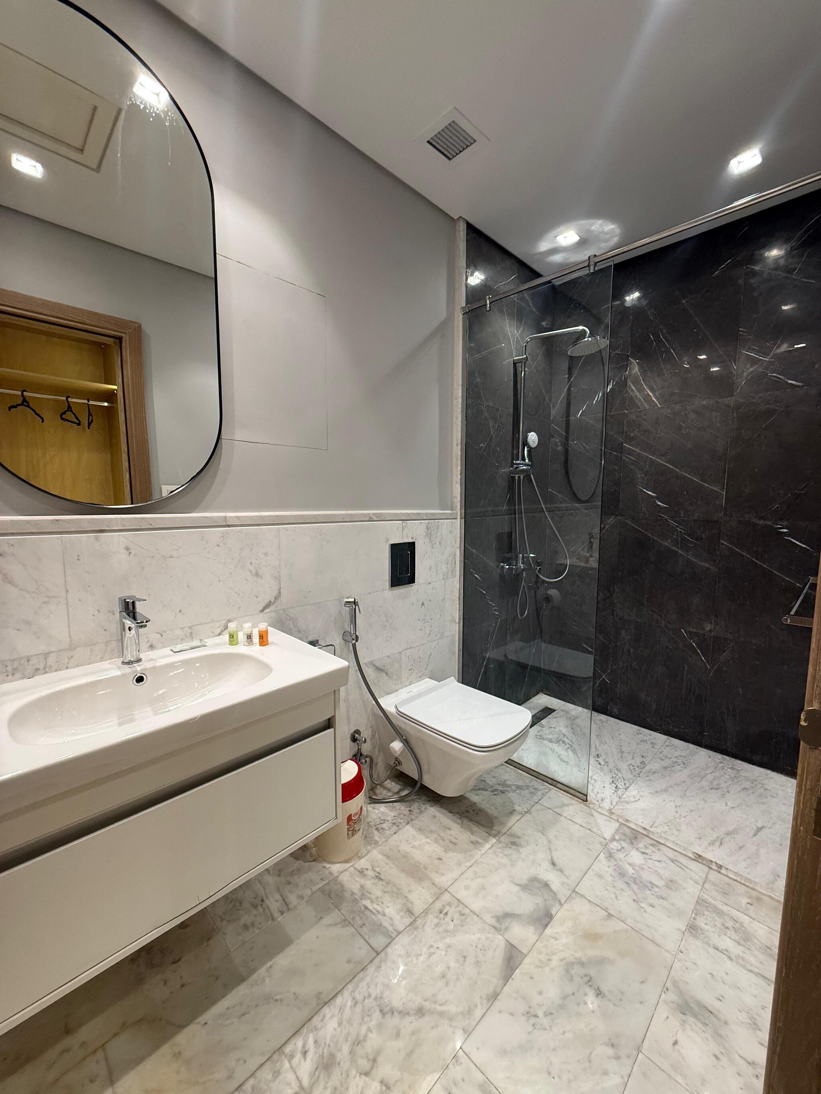 A modern bathroom with a vanity, sink, mirror, and a glass-enclosed shower area.