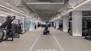 Een sportschool met trainingsapparatuur, een startlijn en een spiegelwand.