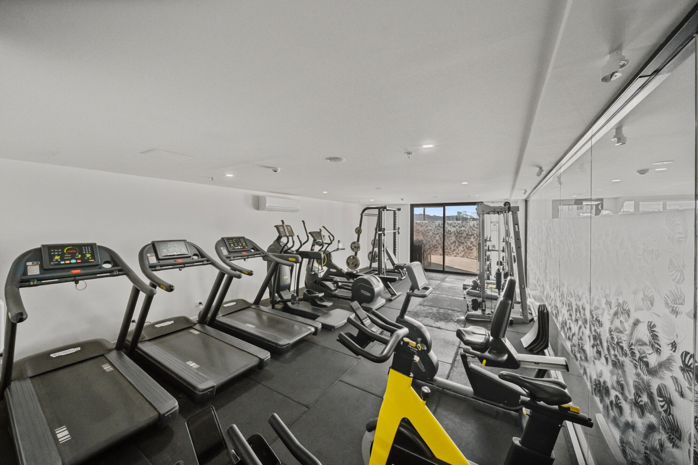 Et fitnesscenter med løbebånd, crosstrainere og styrkeudstyr.