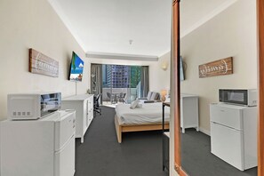 Une chambre d’hôtel équipée d’un lit, d’un bureau, de chaises, d’une télévision, d’un four à micro-ondes et d’un réfrigérateur.